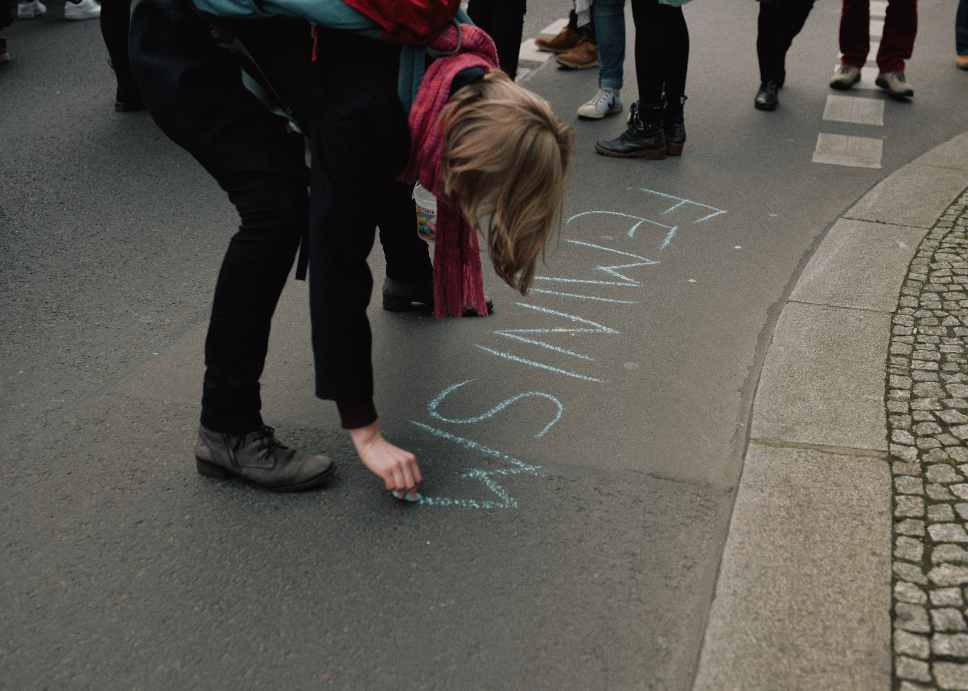 Protestor writes "FEMINISM" in chalk on the street